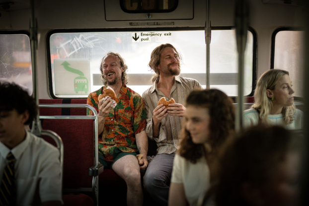 two guys eating and laughing on a bus